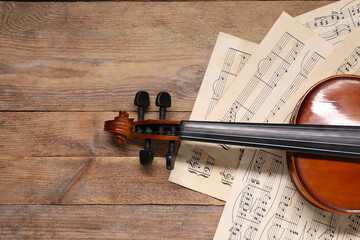 Violin and music sheets on wooden table, top view. Space for text