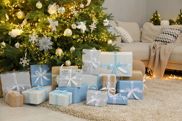 Many gift boxes under decorated Christmas tree in room