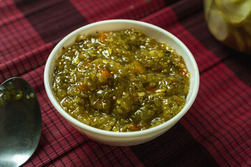 sweet pickle relish in a white bowl, coarse chop of cucumber, pepper and onion with sweet vinegar brine
