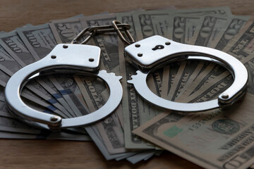 Handcuffs on hundred dollar bills, criminal earnings. Concept: arrest for bribery, bribing an...
