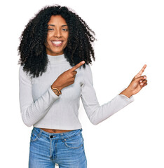 Young african american girl wearing casual clothes smiling and looking at the camera pointing with...
