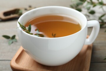 Cup of aromatic eucalyptus tea on wooden table, closeup