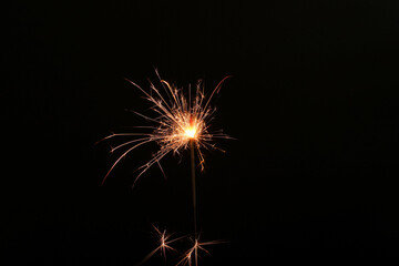 Burning sparkler stick on black background, space for text