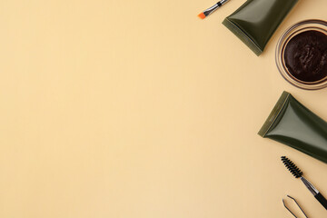 Flat lay composition with eyebrow henna and tools on beige background. Space for text