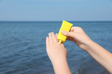 Woman applying sunscreen outdoors, closeup. Sun protection care
