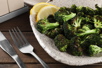 Tasty fried broccoli with lemon served on wooden table, closeup