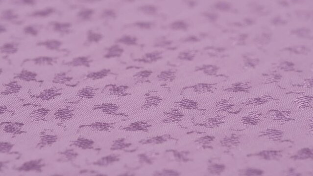 rotation of plain jacquard fabric of lilac color in closeup. macro texture of factory material with woven pattern. textured abstract textile background for textile or clothing industry.