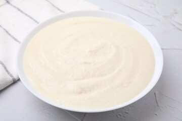 Delicious semolina pudding in bowl on white textured table, closeup