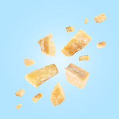 Parmesan cheese in air on light blue background