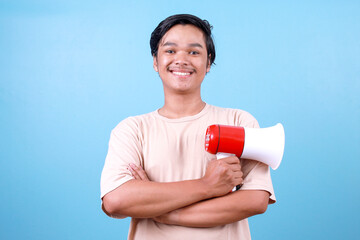 Portrait of cheerful young Asian man holding megaphone and looking at camera smiling