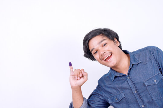 Happy Asian man showing little finger after voting on Indonesia election day  over white background with copy space