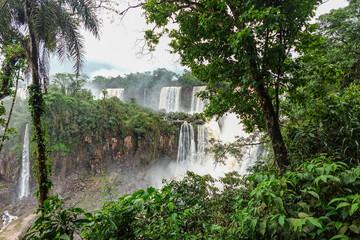Cataratas de Iguazú en el lado argentino rodeados de muchos árboles y con el cielo lleno de nubes
