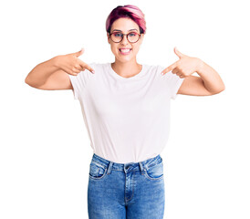 Fototapeta na wymiar Young beautiful woman with pink hair wearing casual clothes and glasses looking confident with smile on face, pointing oneself with fingers proud and happy.
