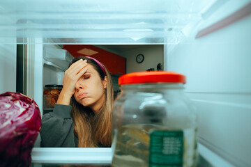 Woman Looking in the Fridge Having Nothing to Eat. Hungry millennial girl searching for a snack in...