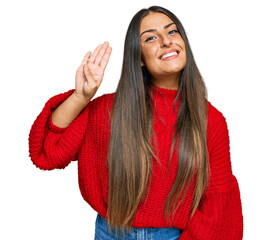 Beautiful hispanic woman wearing casual clothes waiving saying hello happy and smiling, friendly welcome gesture