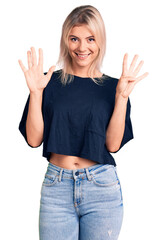 Fototapeta na wymiar Young beautiful blonde woman wearing casual t-shirt showing and pointing up with fingers number nine while smiling confident and happy.
