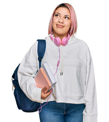 Hispanic woman with pink hair wearing student backpack and headphones smiling looking to the side...