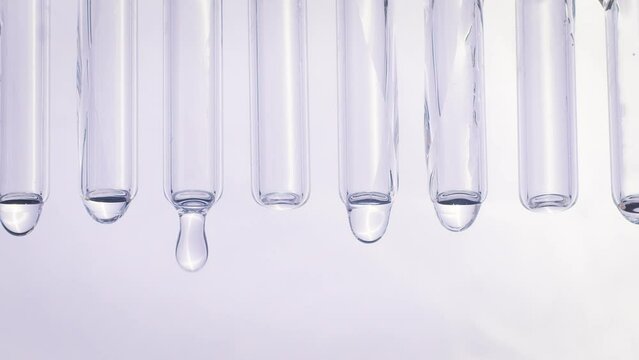 drops of water flow down glass tubes on a white background