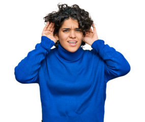 Young hispanic woman with curly hair wearing turtleneck sweater trying to hear both hands on ear gesture, curious for gossip. hearing problem, deaf