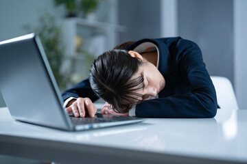 仕事中に寝てしまうスーツを着た女性