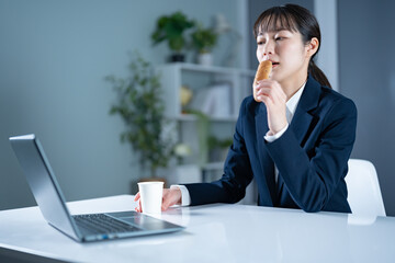 仕事中に菓子パンを食べる女性