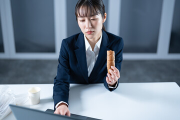 仕事中に菓子パンを食べる女性
