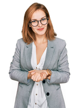 Young caucasian woman wearing business style and glasses with hands together and crossed fingers smiling relaxed and cheerful. success and optimistic