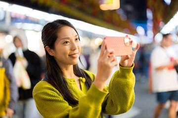 Woman use cellphone to take photo in street market