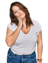 Young plus size woman wearing casual white t shirt thinking looking tired and bored with depression problems with crossed arms.