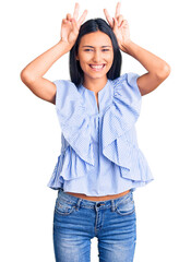 Young beautiful latin girl wearing casual clothes posing funny and crazy with fingers on head as bunny ears, smiling cheerful