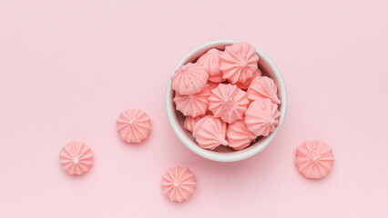 Top view of a bowl with meringue on a pink background.