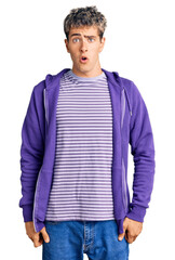 Fototapeta premium Young handsome man wearing casual purple sweatshirt afraid and shocked with surprise expression, fear and excited face.