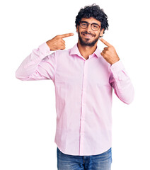 Handsome young man with curly hair and bear wearing business clothes smiling cheerful showing and pointing with fingers teeth and mouth. dental health concept.