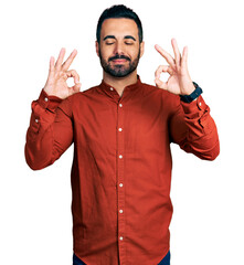 Young hispanic man with beard wearing casual shirt relaxed and smiling with eyes closed doing meditation gesture with fingers. yoga concept.