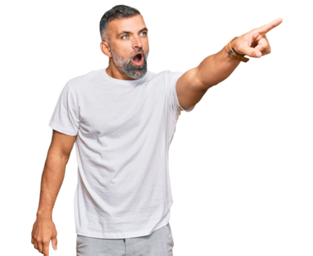 Middle age handsome man wearing casual white tshirt pointing with finger surprised ahead, open mouth amazed expression, something on the front