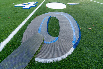 Synthetic turf field under construction with lines and graphics being installed.	