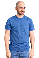 Young handsome man wearing casual t shirt looking away to side with smile on face, natural expression. laughing confident.