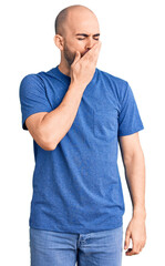 Young handsome man wearing casual t shirt bored yawning tired covering mouth with hand. restless and sleepiness.
