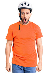 Young handsome man wearing bike helmet scared and amazed with open mouth for surprise, disbelief face