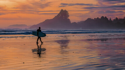 Tofino beach Vancouver Island Pacific rim coast during sunset, surfers with surfboard during sunset...