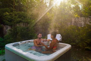 couple in a hot tub bath in the rain forest of Vancouver Island, men and women in an outdoor...