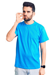 Young handsome man with beard wearing casual t-shirt mouth and lips shut as zip with fingers. secret and silent, taboo talking