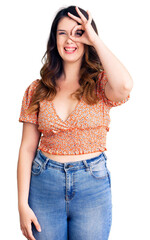 Fototapeta premium Beautiful young brunette woman wearing casual clothes doing ok gesture with hand smiling, eye looking through fingers with happy face.