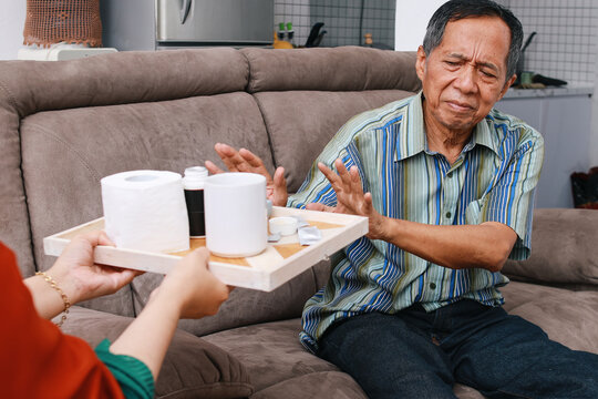 Asian old man rejecting to take some medicines