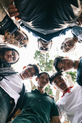 Group of young people standing in circle looking at low angle camera.