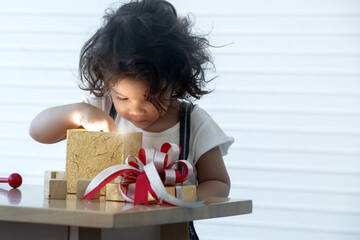 Cute little girl pays attention to gift box, opened it on purpose and look inside