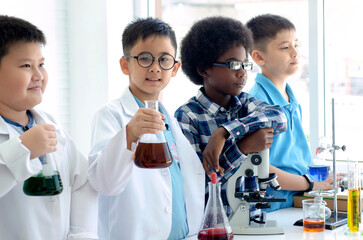 Group of multiracial school child boy stood and holding experiment flasks in a line and looked...