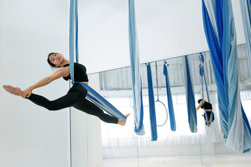 Young woman is practicing aerial dancing using a hammock to dance