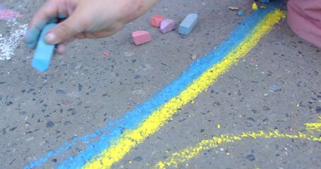 Street artists hand close up, creating yellow and blue stripes. Drawings on the asphalt to decorate public spaces and add color to the urban environment, means of conveying a message or idea. 