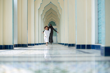 Happy Muslim mother in Nigab and her child son in traditional clothes running and playing in the...